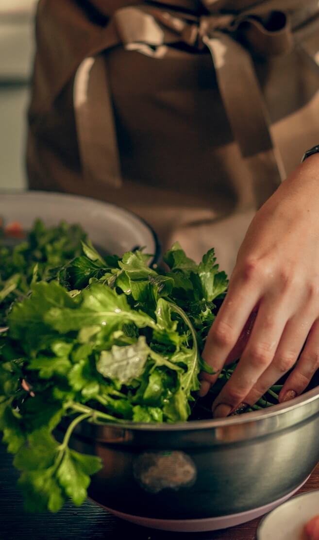 Person preparing greens in kitchen