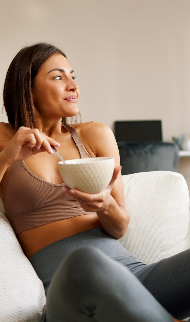 woman sitting on couch eating out of bowl